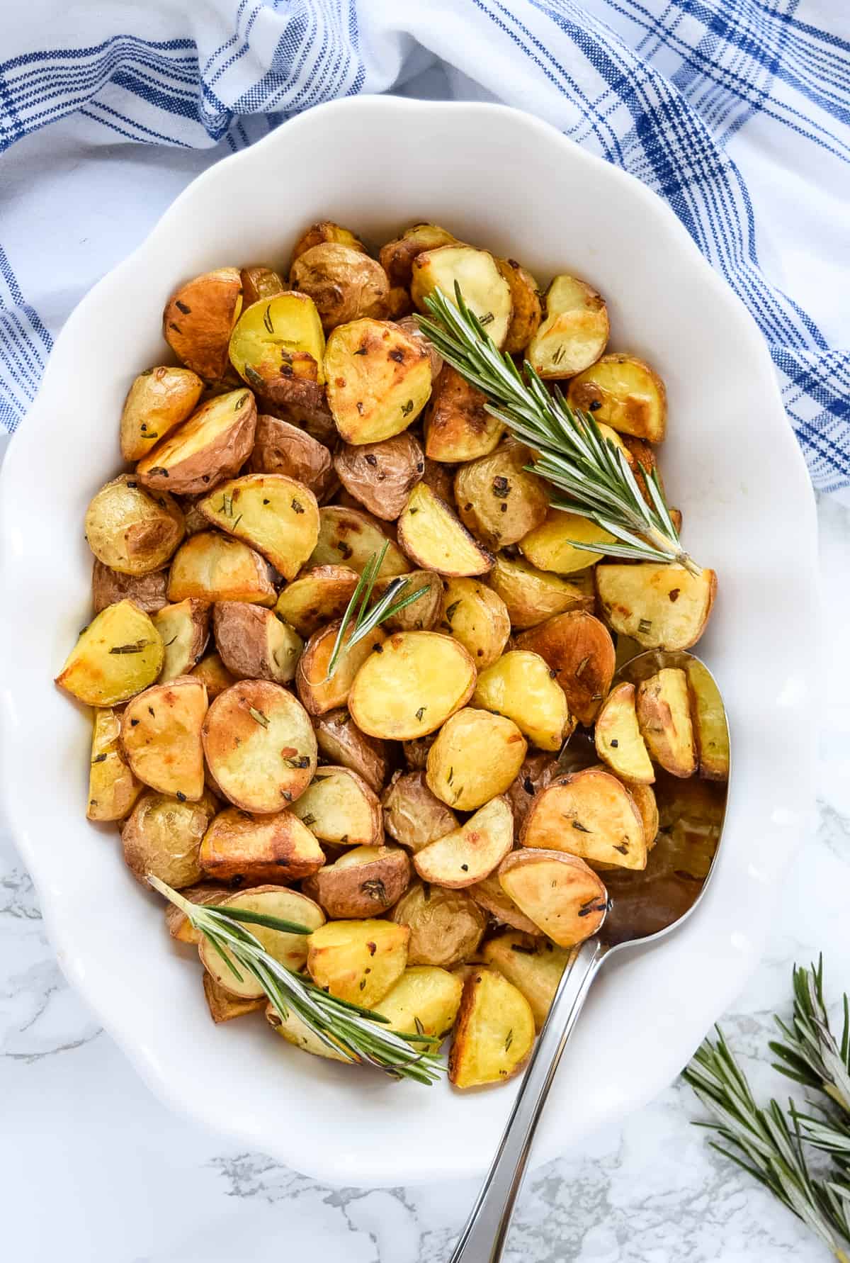 Garlic Rosemary Roasted Potatoes in a white serving bowl with a spoon.