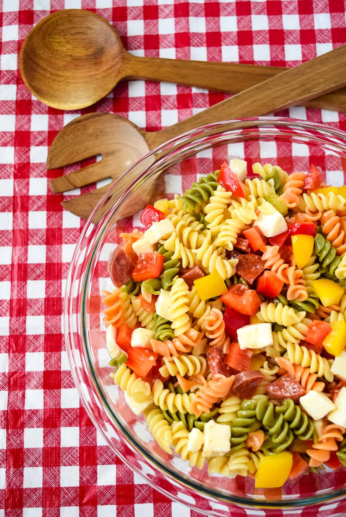 Zesty Italian Pasta Salad in a clear bowl on a picnic table.