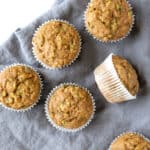 Applesauce Zucchini Muffins on a white countertop with a blue linen napkin.