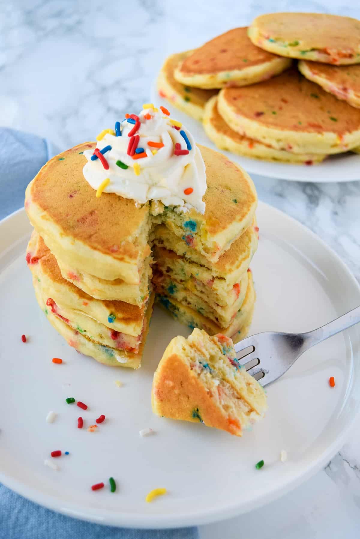 Pancakes with Sprinkles on a white plate with a fork.