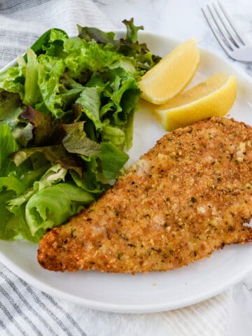 Air Fryer Parmesan Crusted Chicken on a white plate with a salad.