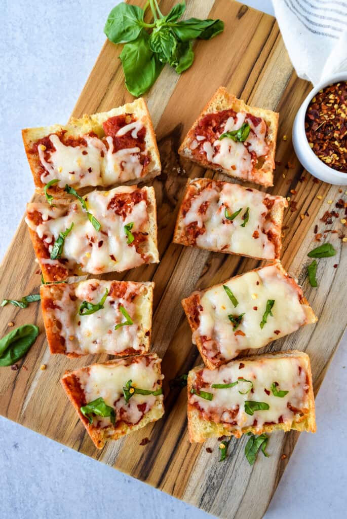 Air Fryer French Bread Pizza cut into 8 pieces on a cutting board.