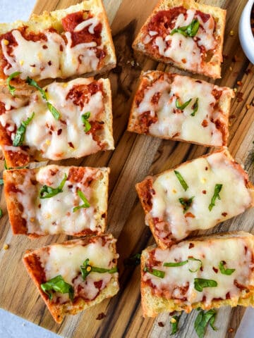 Air fryer french bread pizza cut into slices on a cutting board.