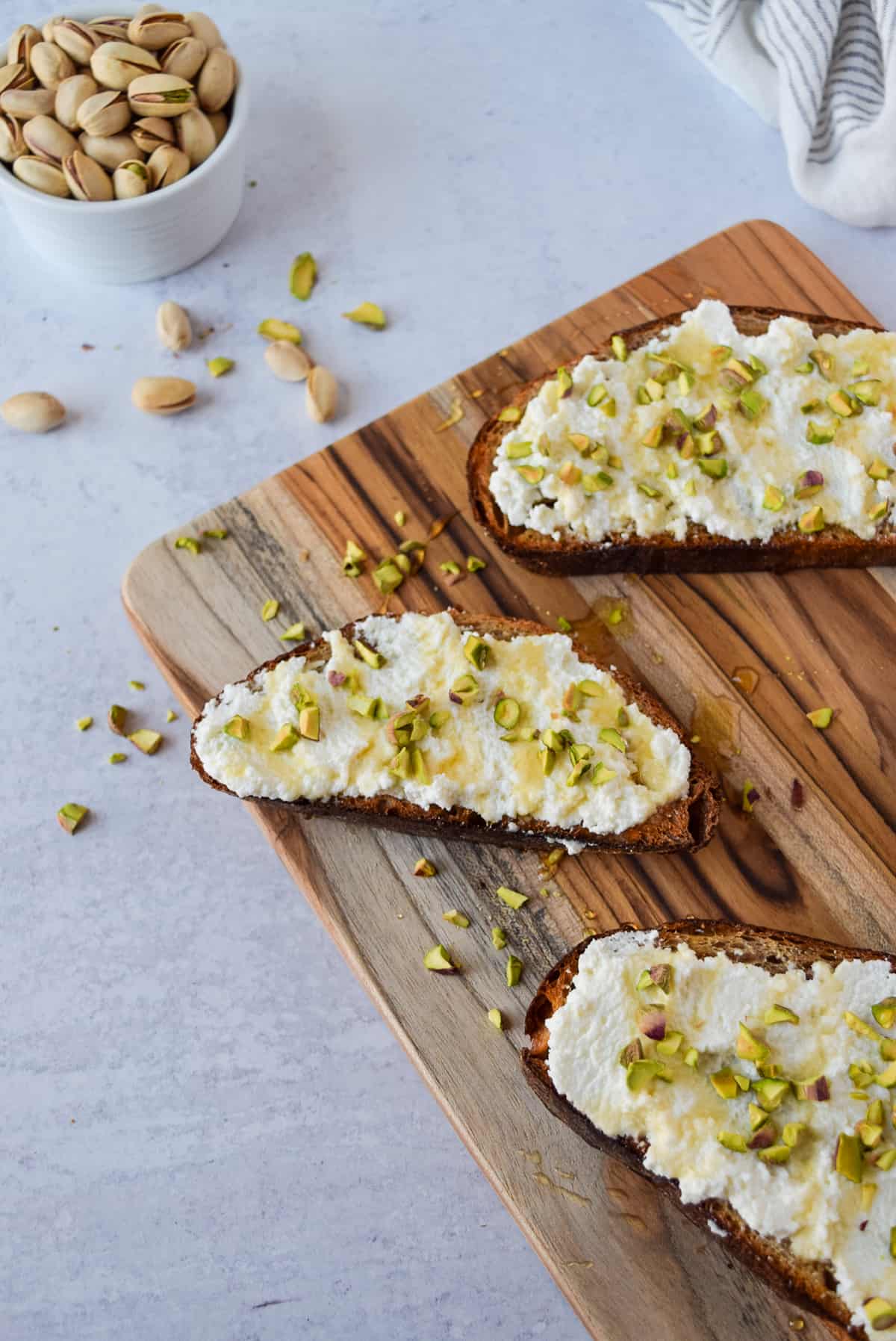 Ricotta Honey Toast with Pistachios on a cutting board.