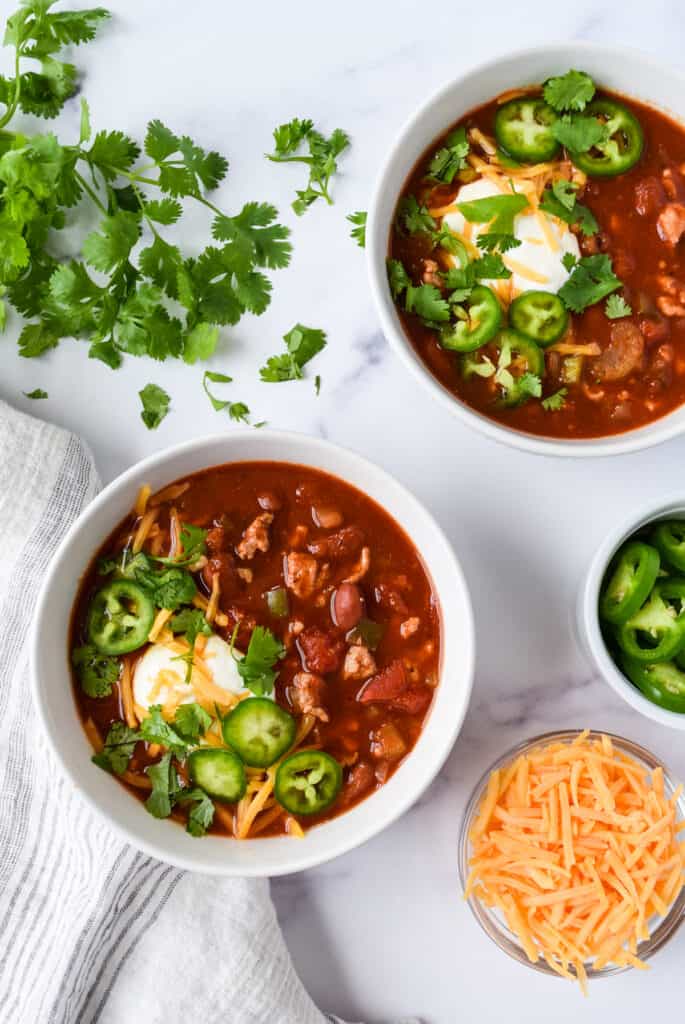 Slow Cooker Turkey and Bean Chili with cheddar cheese, cilantro, and jalapeños.