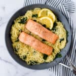 Lemon Kale Pasta with Salmon in a skillet with lemon wedges.