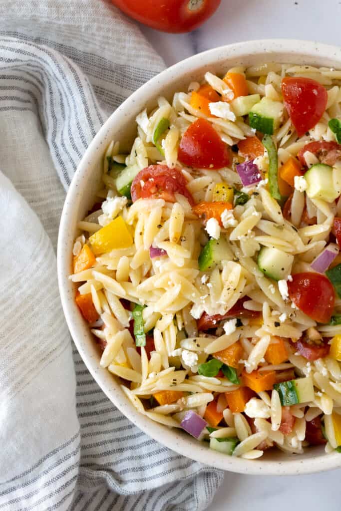 Rainbow Orzo Salad in a bowl on a table with a linen.