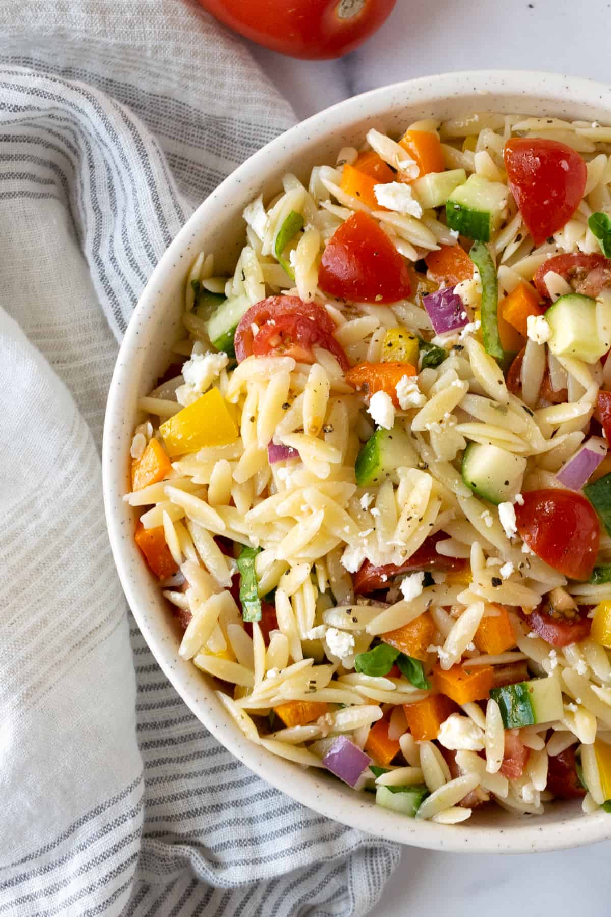This is a photo of Rainbow Orzo Salad served in an off-white serving bowl.