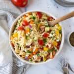 Rainbow Orzo Salad on a table with 3 small stacked plates and forks.