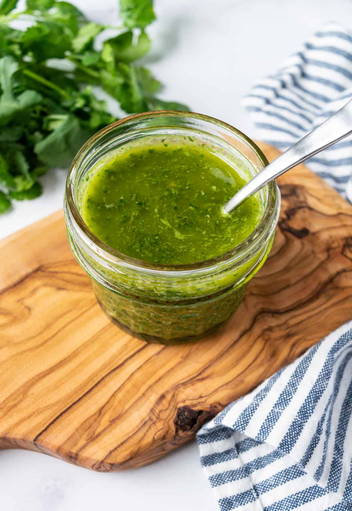 Cilantro Lime Vinaigrette in a glass jar with a spoon in it.