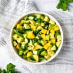 Cucumber Mango Salad with Avocado in a white bowl with cilantro.