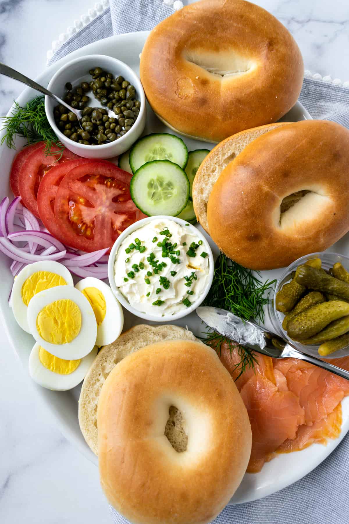 Smoked Salmon Bagel on a white plate with pickles and hard boiled egg.