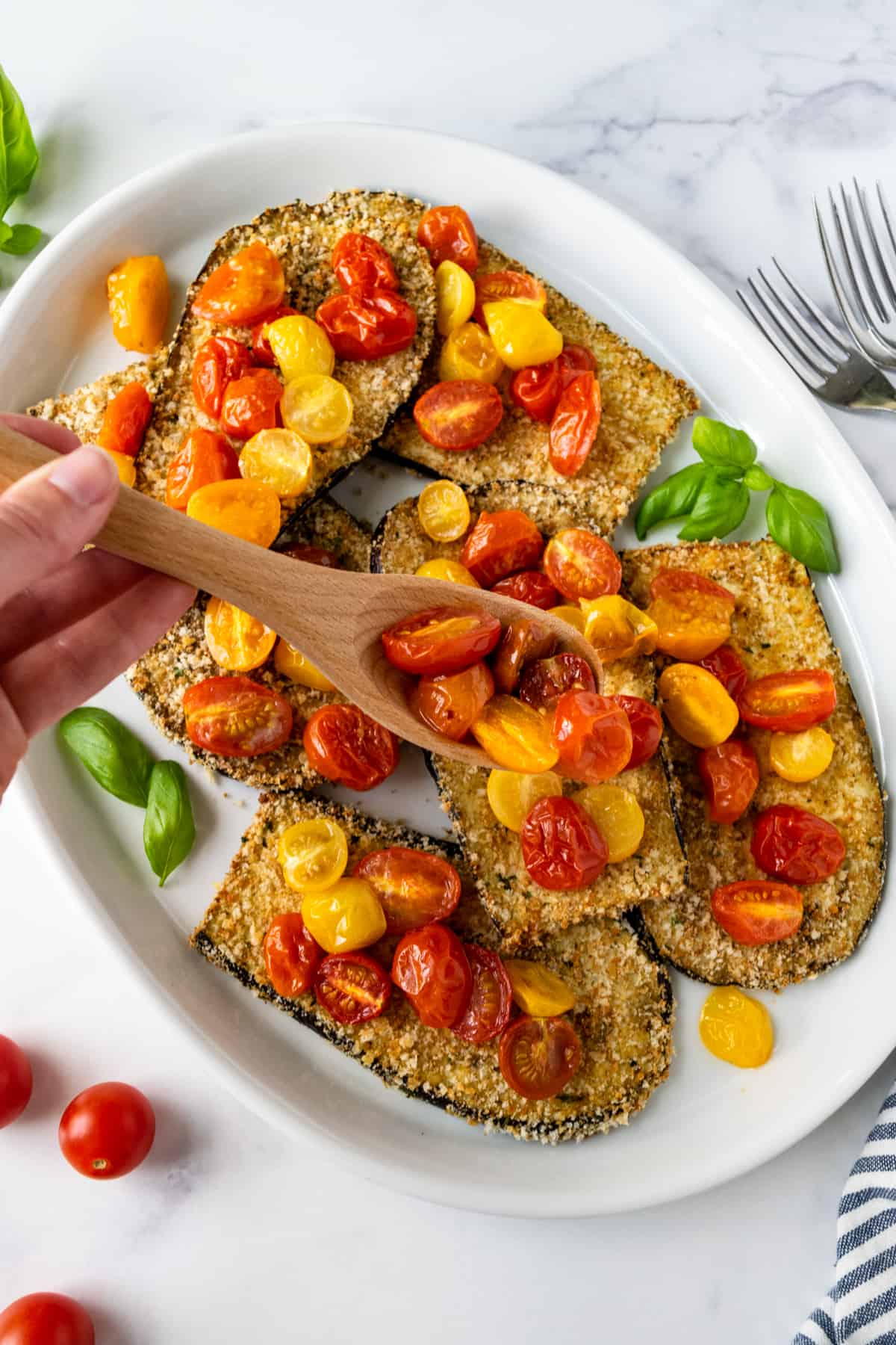 Crispy Baked Eggplant with Cherry Tomatoes on a white plate.