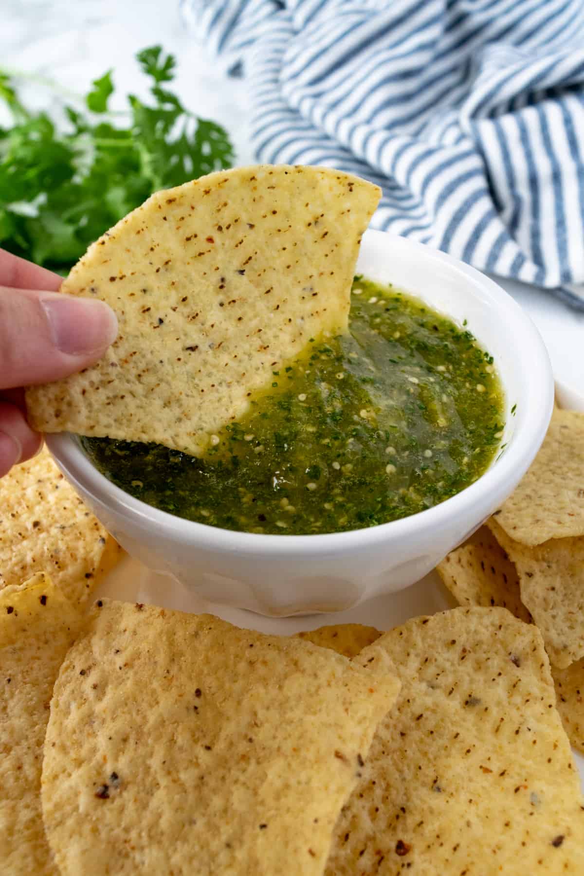 Homemade Restaurant Style Salsa Verde with someone dipping a chip into it.