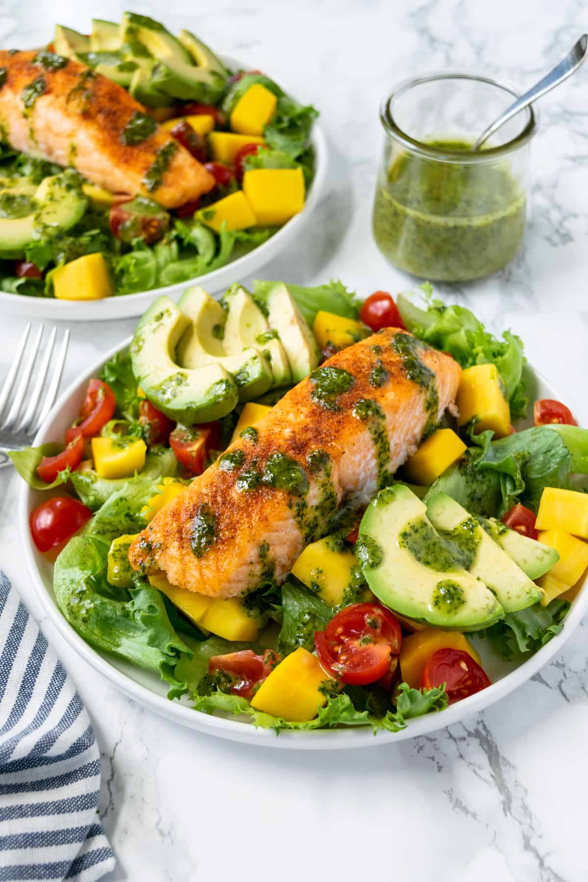 Mango Salmon Salad on a plate with cilantro lime vinaigrette in a jar in the background.
