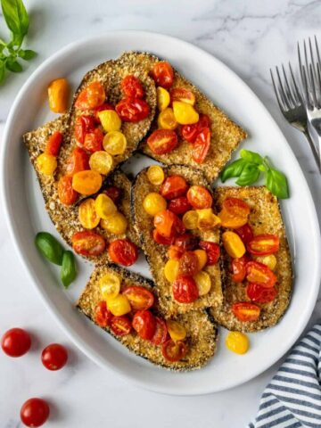 Crispy Baked Eggplant with Cherry Tomatoes on a white platter.