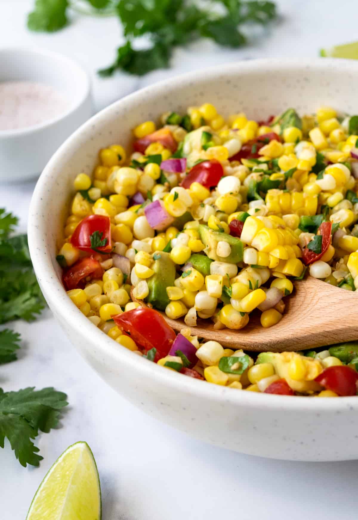 Fiesta Corn Salad with Avocado in a bowl with a serving spoon.