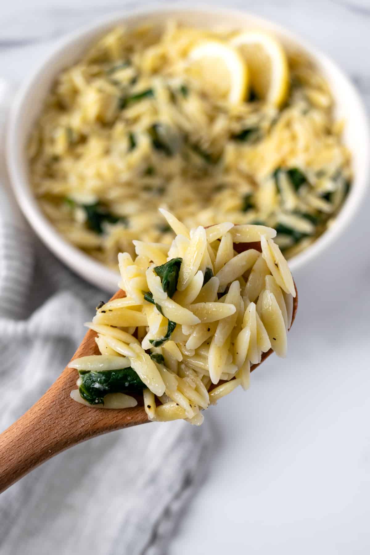 Lemon Orzo with Spinach on a wooden spoon.