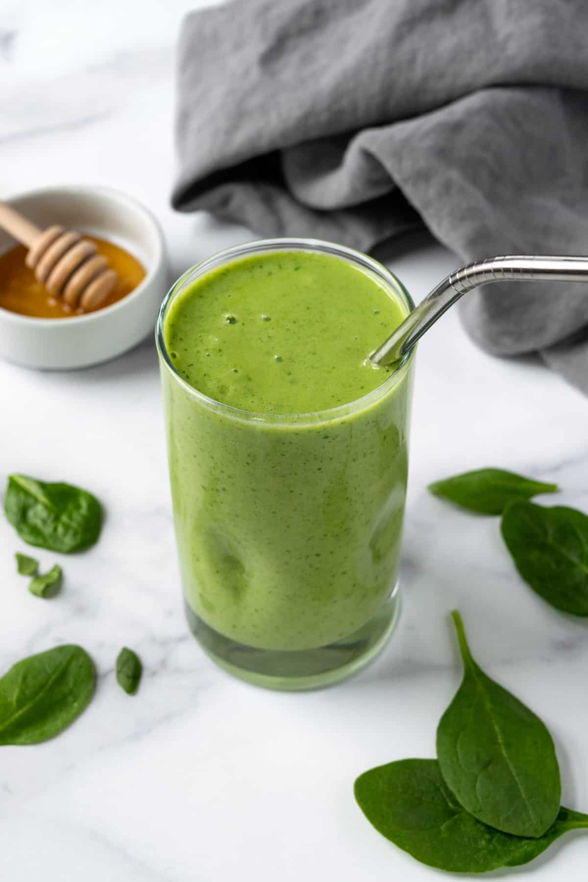 Mango Spinach Smoothie in a glass with a metal straw.
