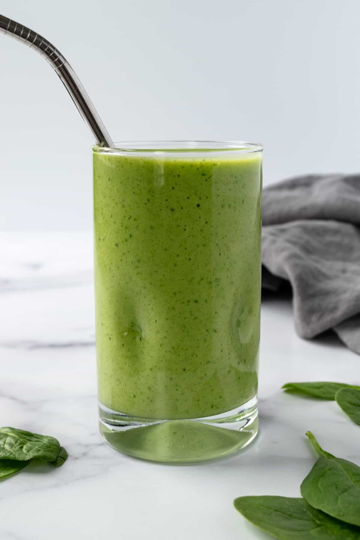 Mango Spinach Smoothie in a glass with a straw.