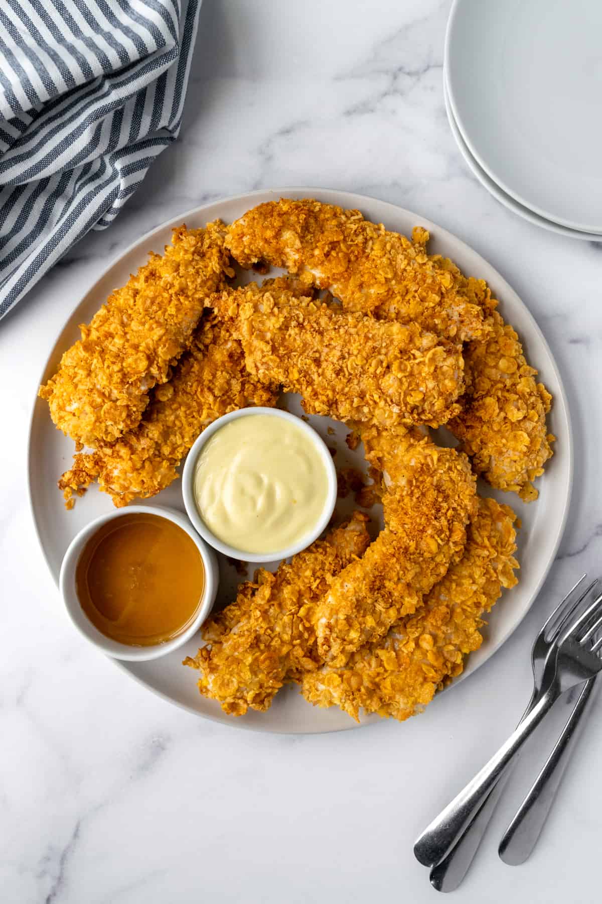 Baked Cornflake Chicken Tenders on a plate with dipping sauces.