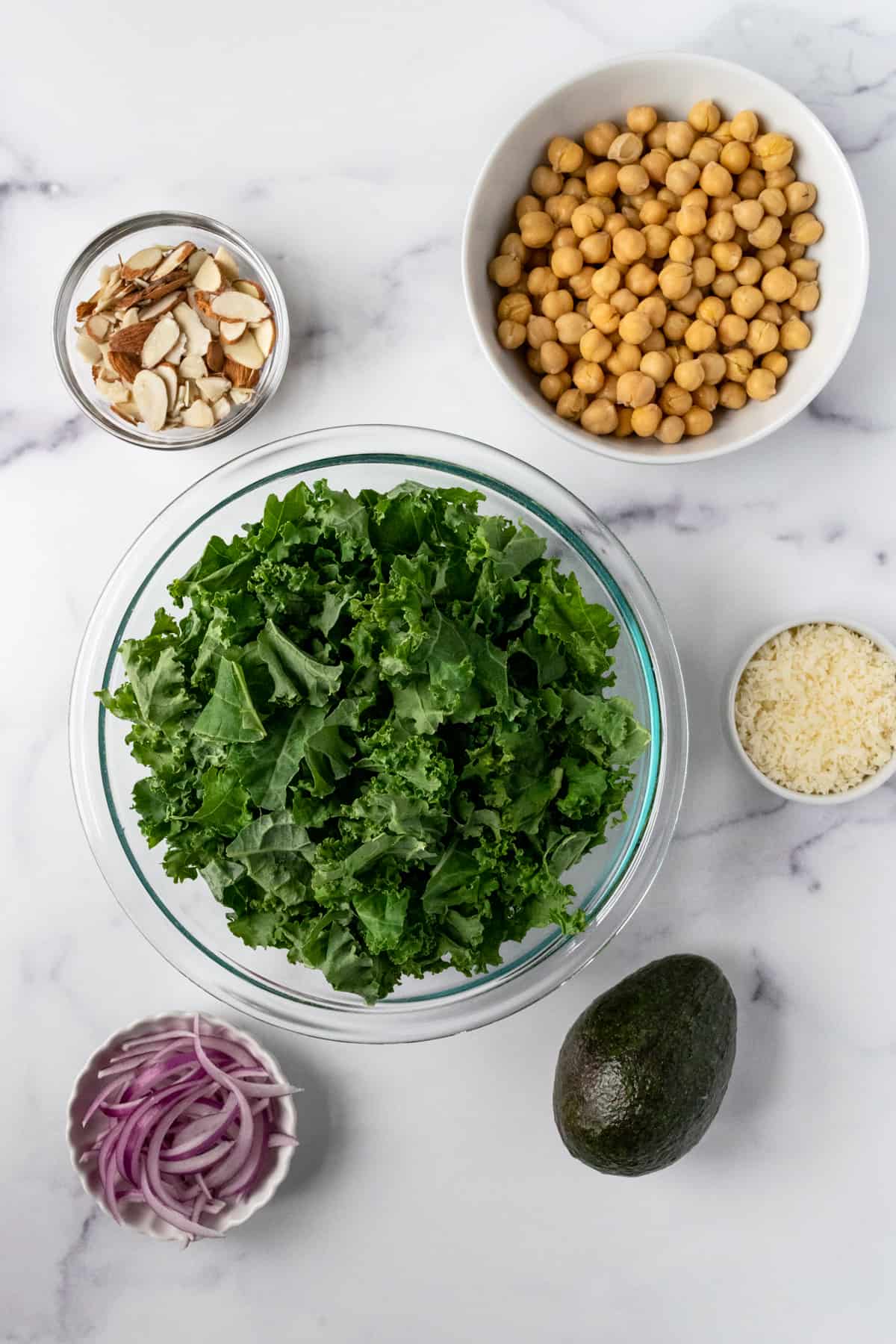 Ingredients including Kale, Chickpeas, sliced almonds, parmesan, avocado and red onion