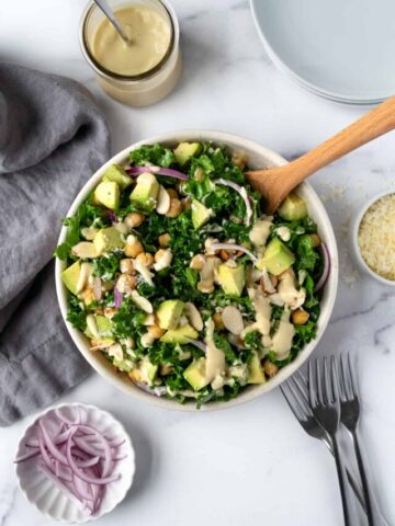 Kale Salad with Tahini Dressing on a table with a serving spoon.