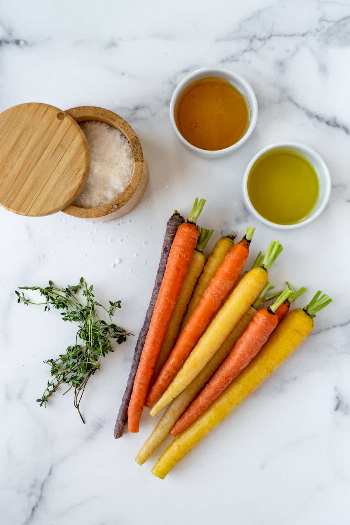 Rainbow Carrots, Fresh Thyme, Sea Salt, Honey, Olive Oil on a countertop