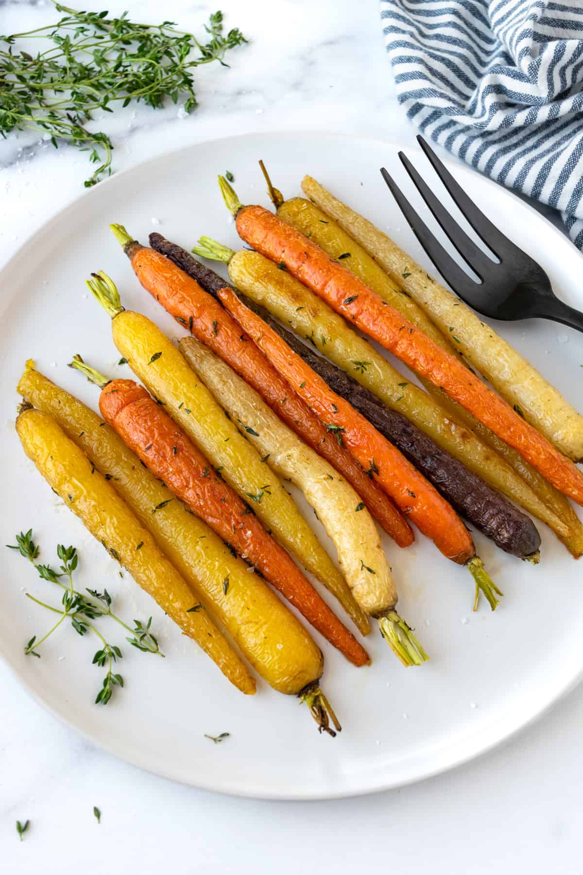 Honey Thyme Roasted Rainbow Carrots on a white serving plate with a serving fork.