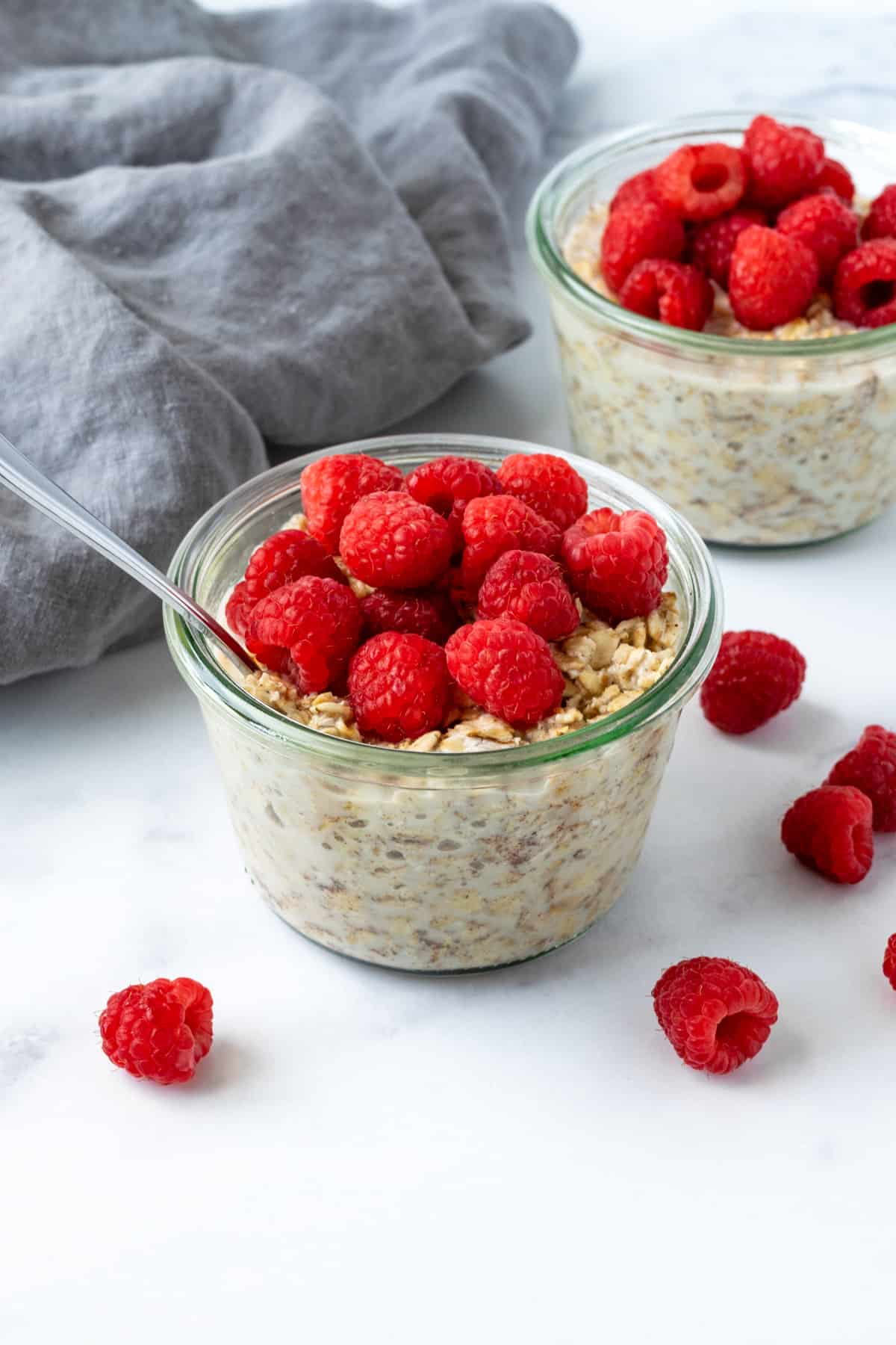 Overnight Oats with Raspberries on a marble countertop with raspberries spread on the table.