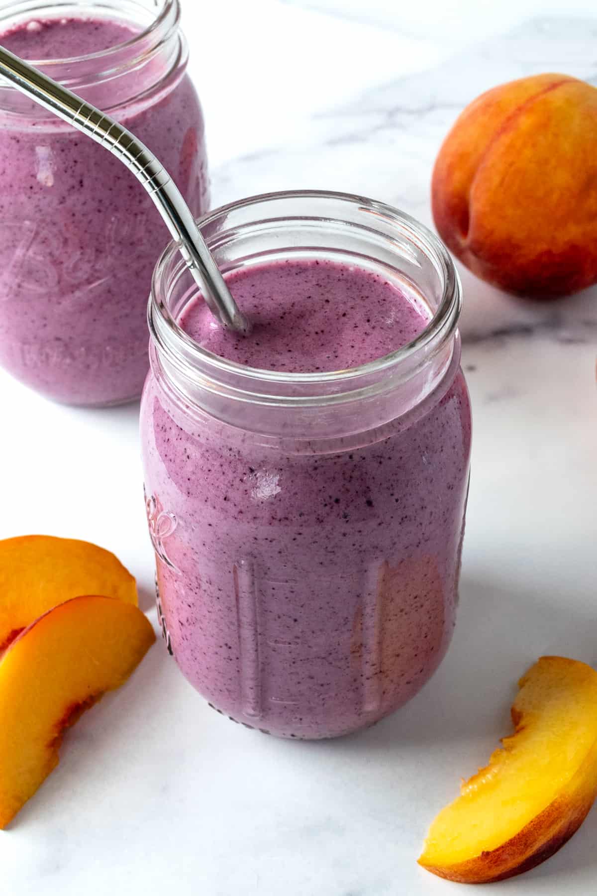 Peach and Blueberry Smoothie in a Mason Jar with a metal straw.