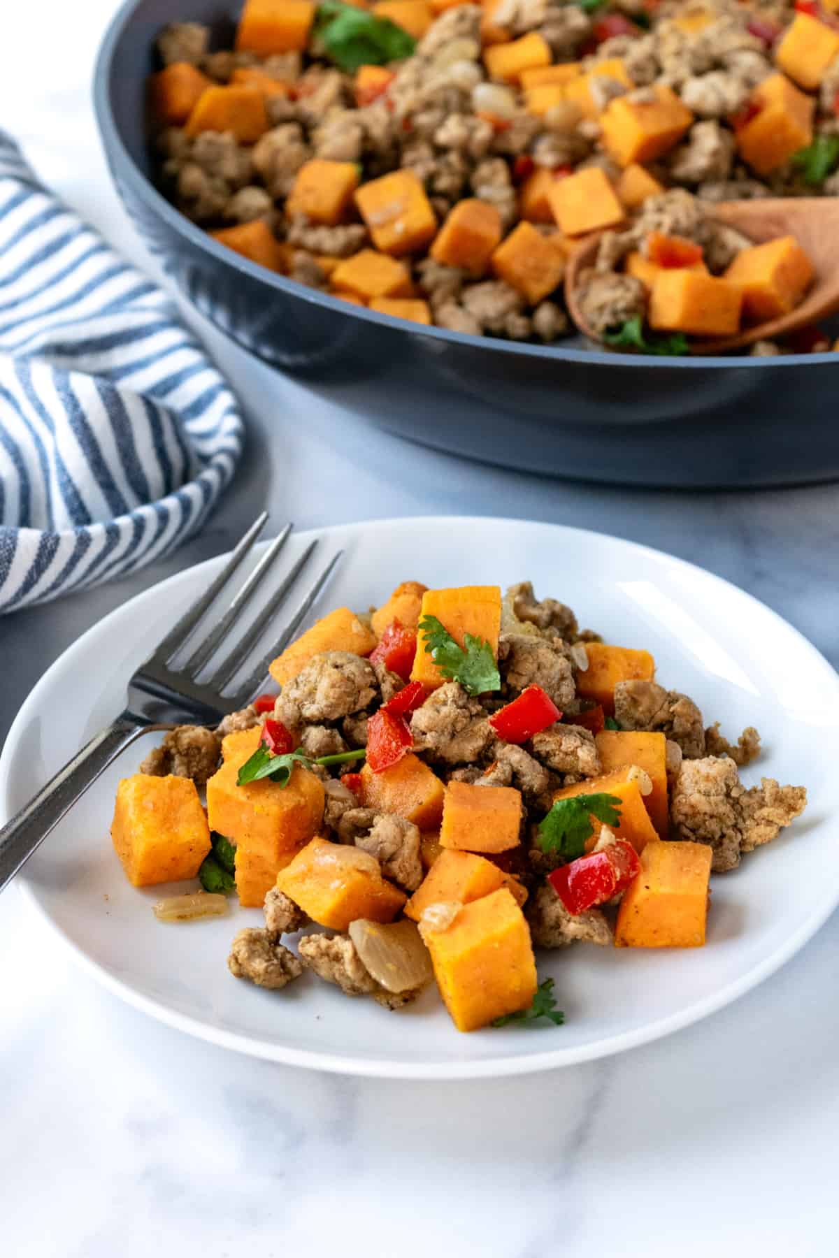 A serving of Sweet Potato Turkey Hash on a white plate with a fork.