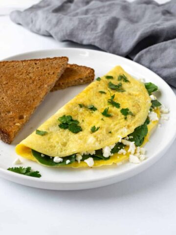 Spinach and Feta Omelet on a white plate with wheat toast.
