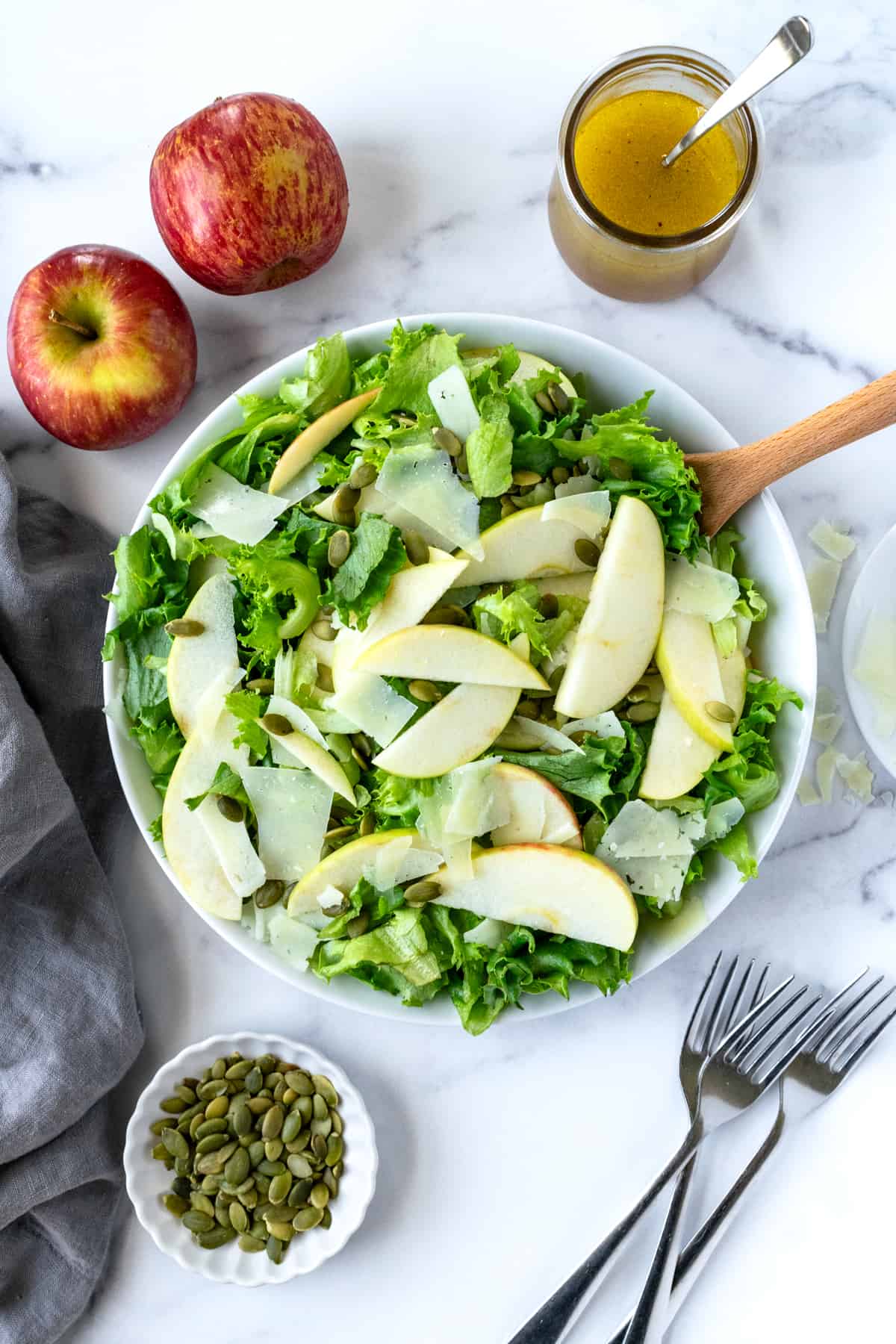 Manchego Apple Salad in a white serving bowl with a wooden spoon.