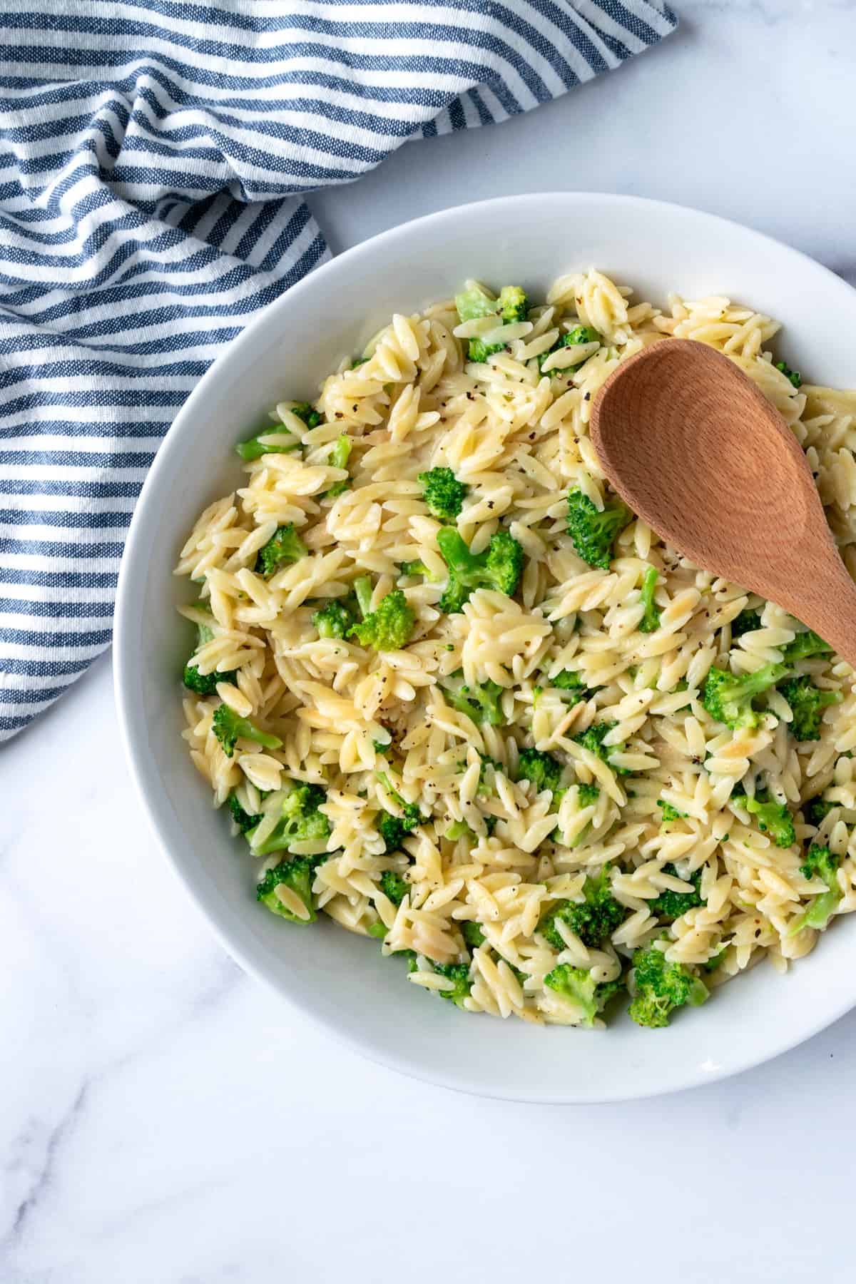 A white serving bowl with broccoli orzo.