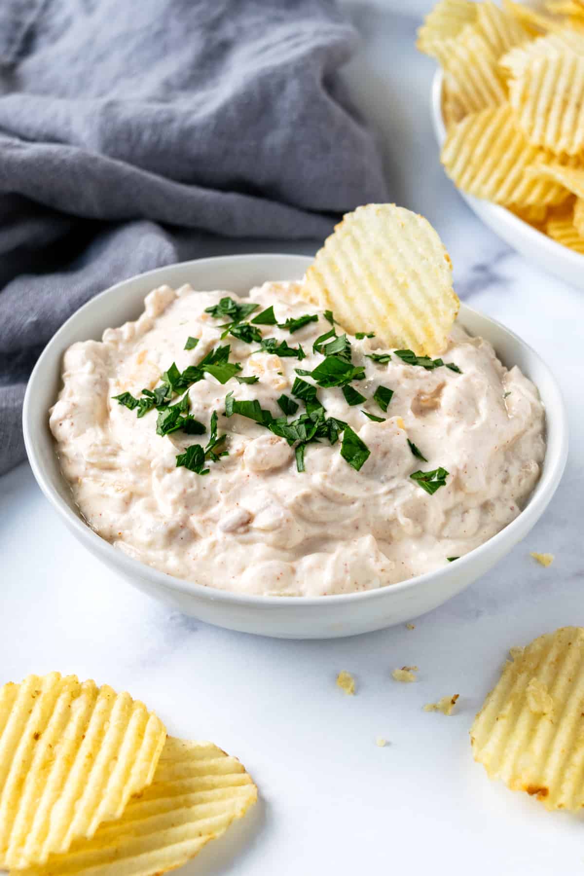 Greek Yogurt French Onion Dip in White Bowl with Chip in it.