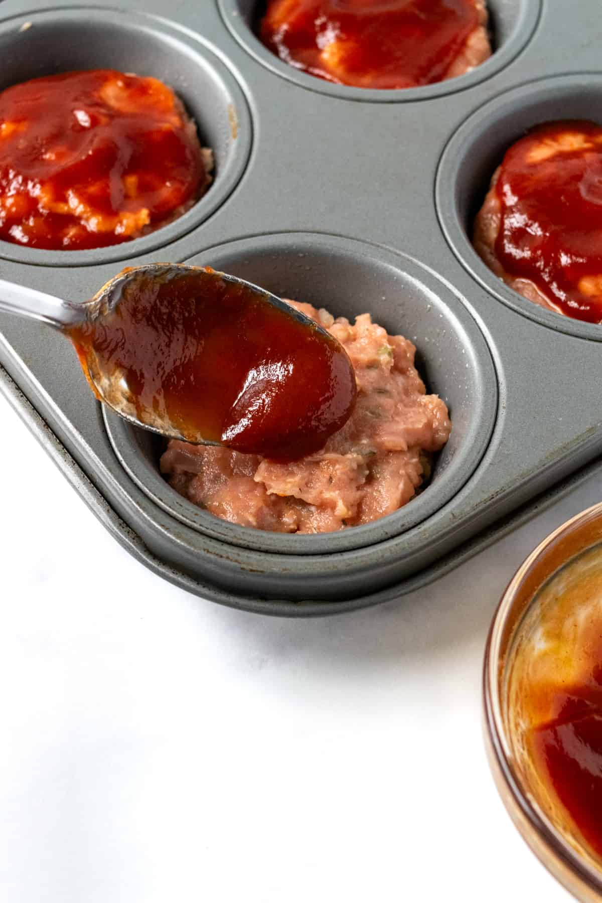 Spooning Sauce Over Turkey Meatloaf Muffins.