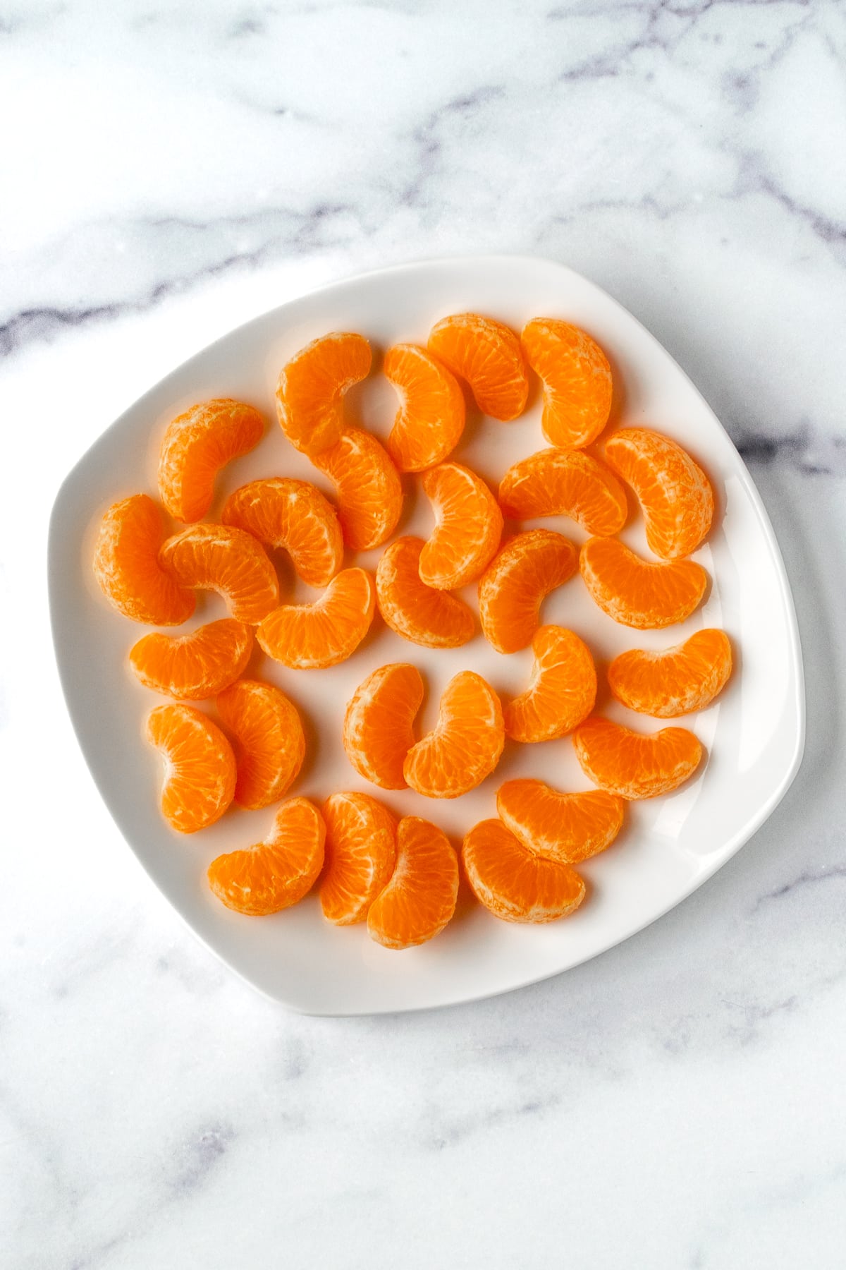 Peeled mandarin orange slices on a white plate.