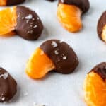 Chocolate Covered Oranges with flaky sea salt on white parchment paper.