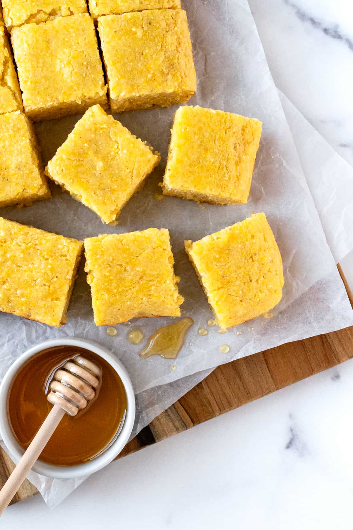 Honey Glazed Cornbread cut into squares on a parchment lined serving board.
