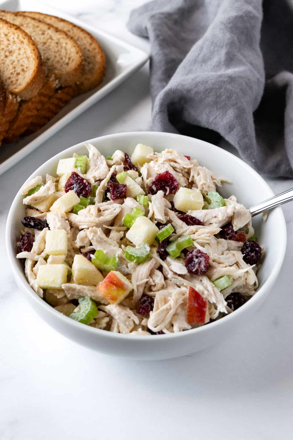 Apple Cranberry Chicken Salad in a White Bowl with a Spoon.