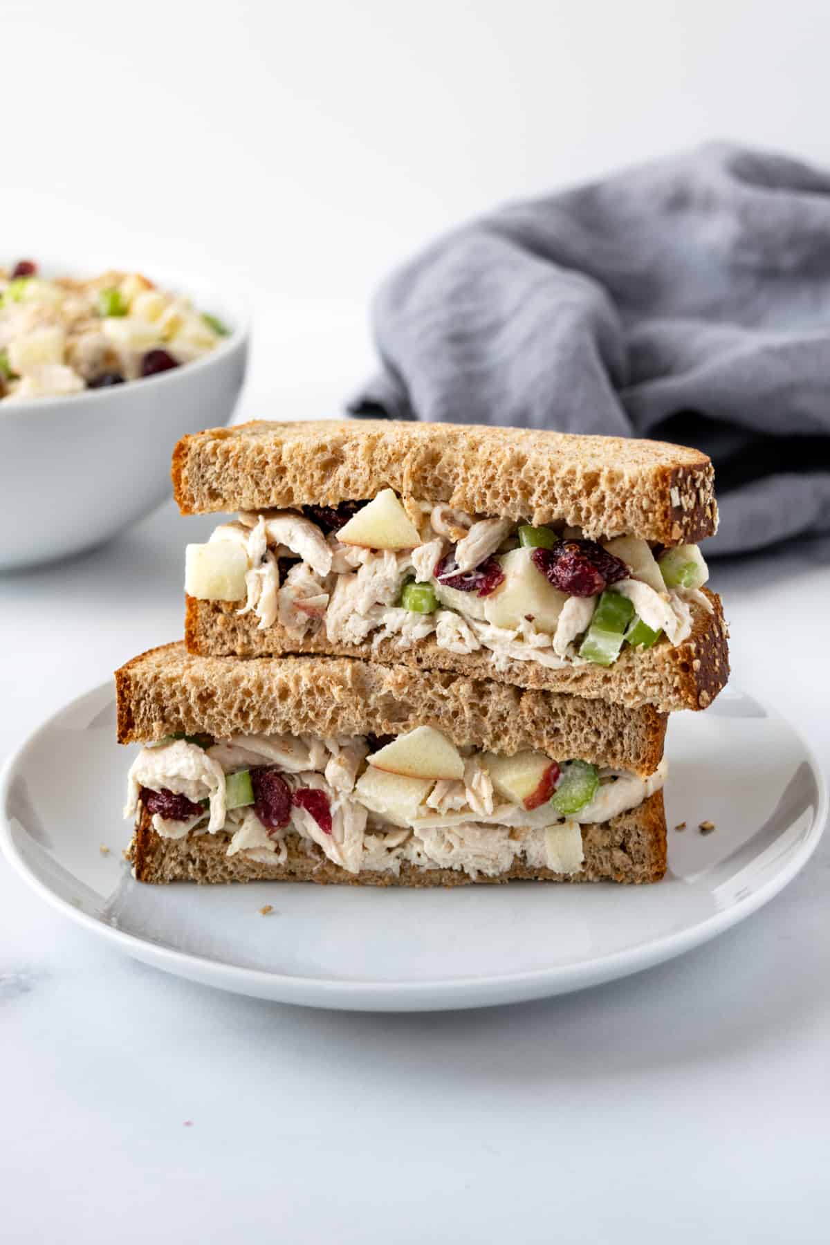 Apple Cranberry Chicken Salad Sandwiches stacked on a white plate.