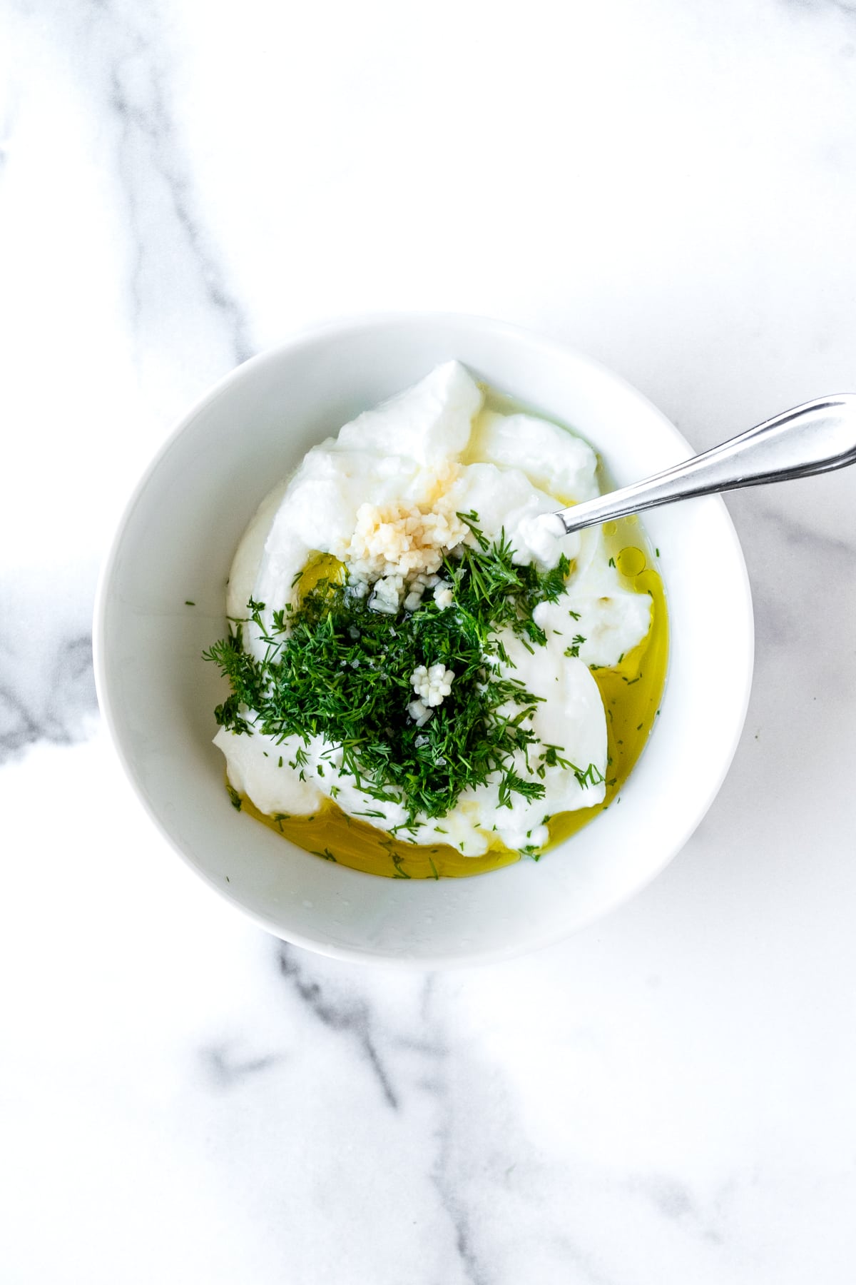 Greek Yogurt Dill Dip Ingredients in a white bowl with a spoon.