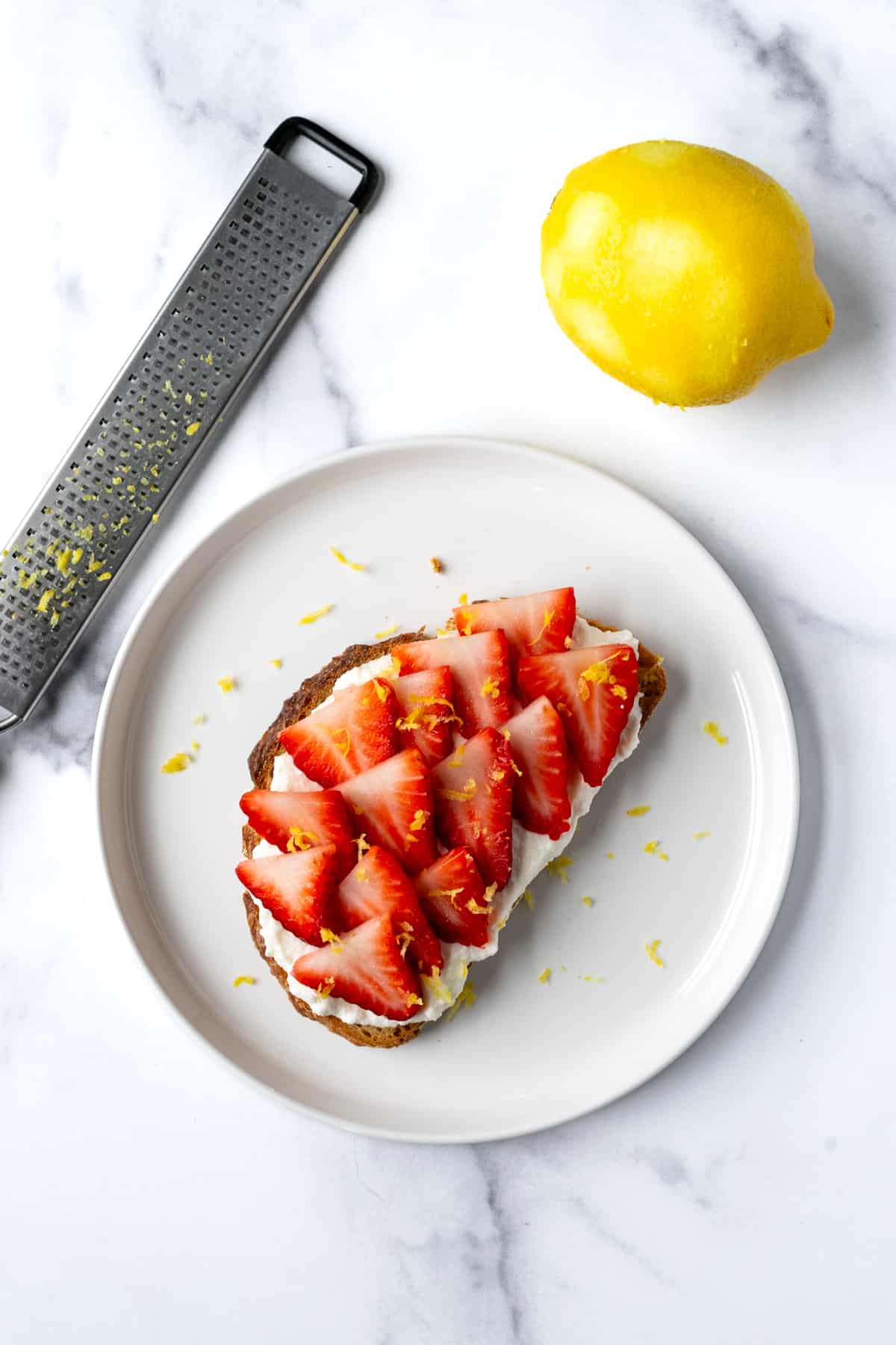 Strawberry Ricotta Toast on a white plate with lemon zest.