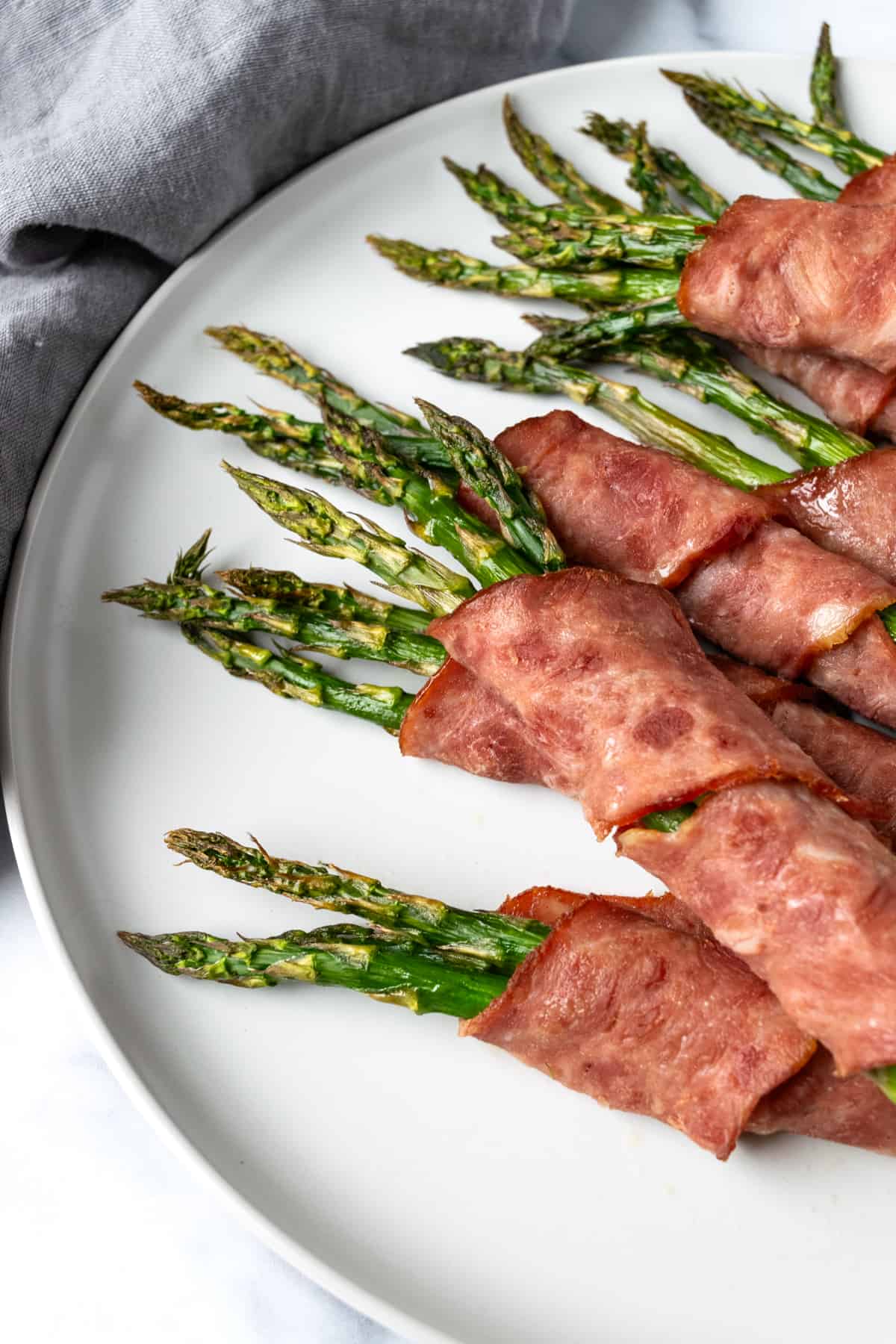 Turkey Bacon Wrapped Asparagus on a white plate.