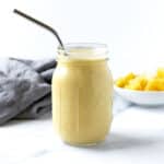 Mango Pineapple Smoothie in a glass on a marble counter.