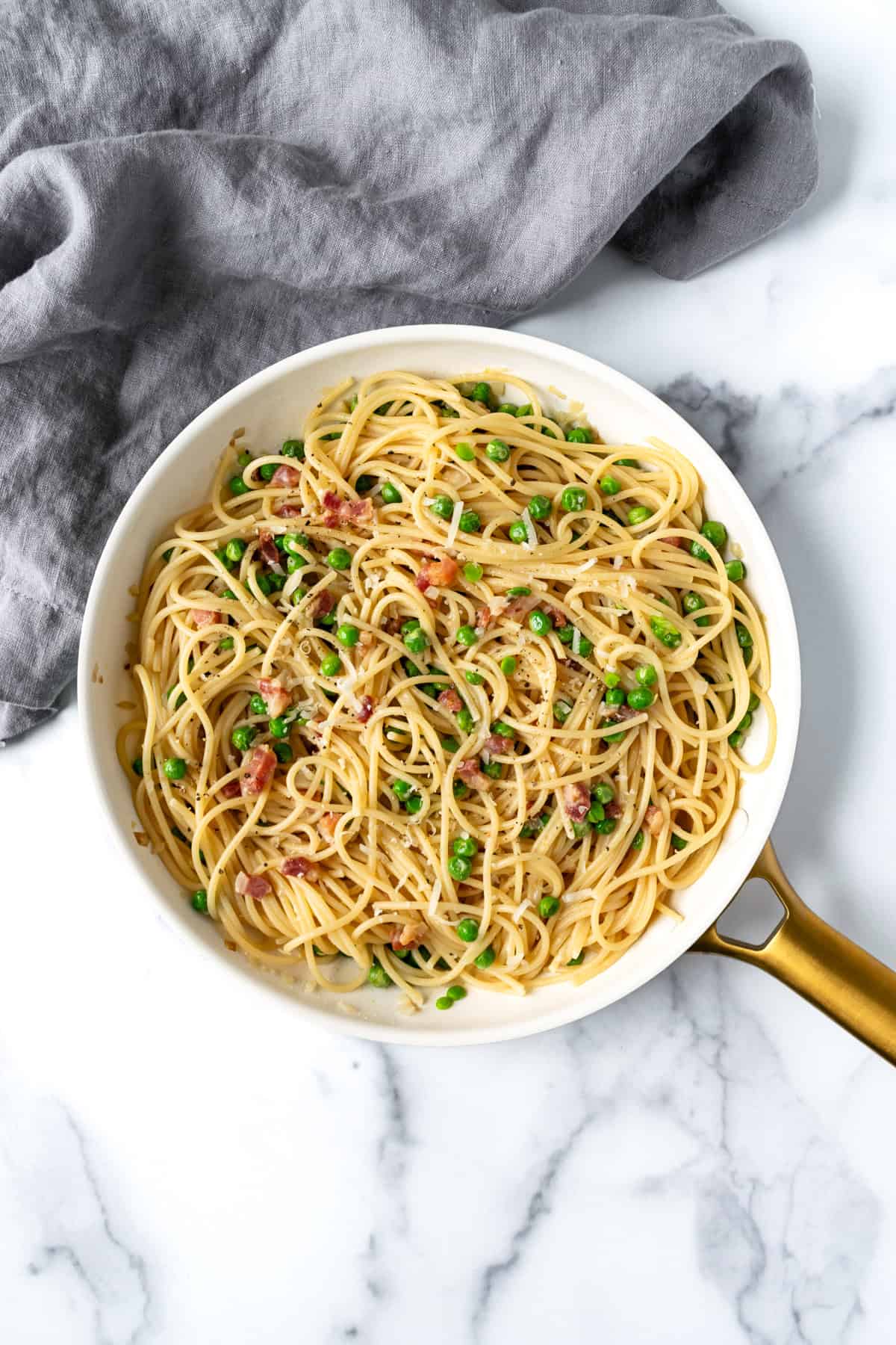 Spaghetti with Pancetta and Peas in a white skillet.