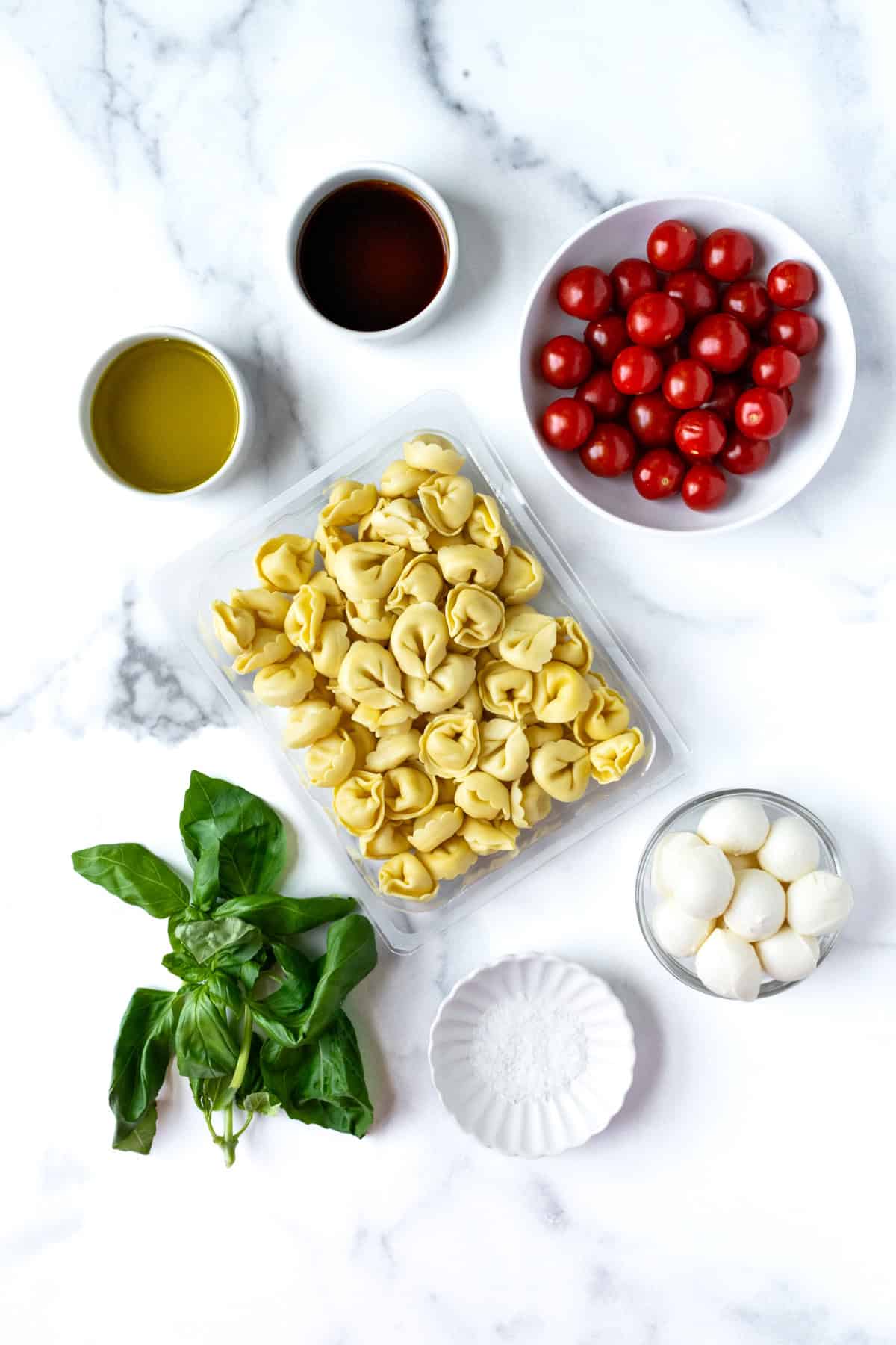 Caprese Tortellini Salad Ingredients on a marble countertop.