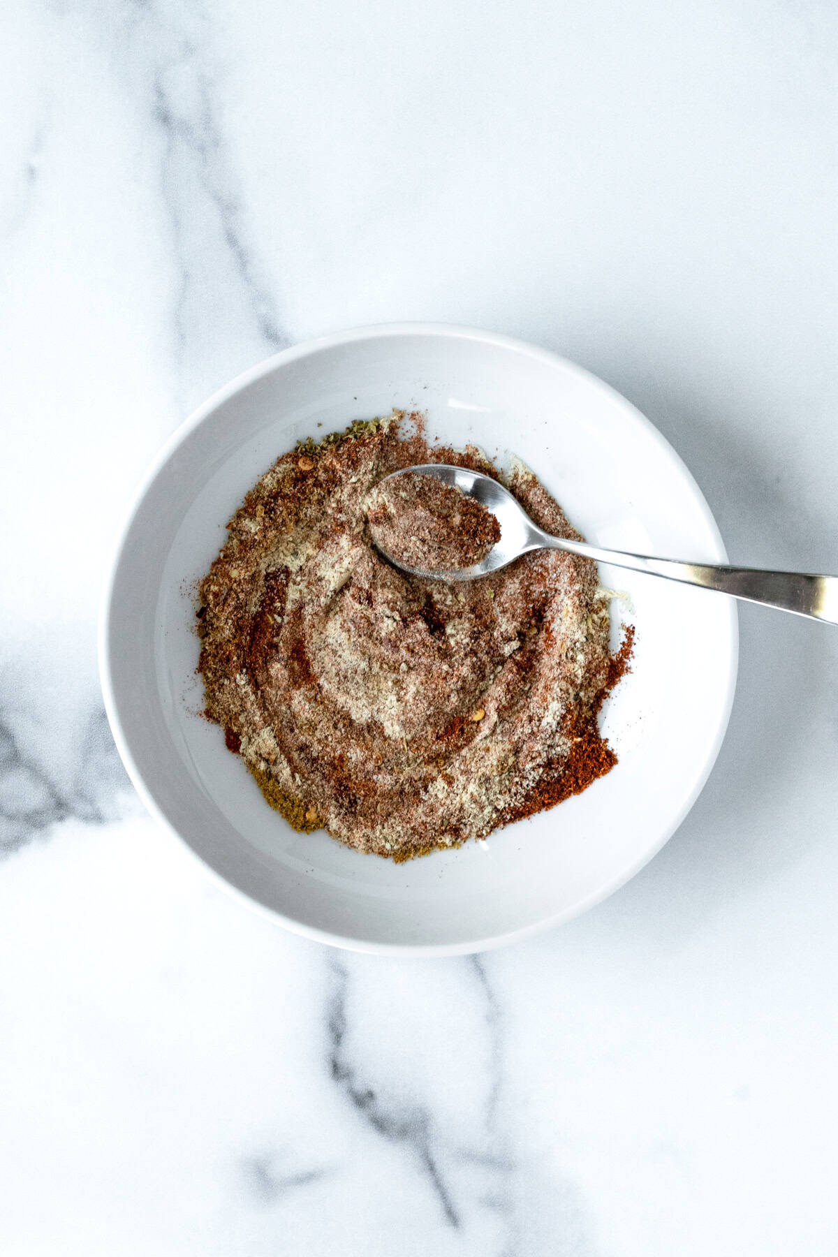 Homemade Turkey Taco Seasoning in white bowl with a spoon.