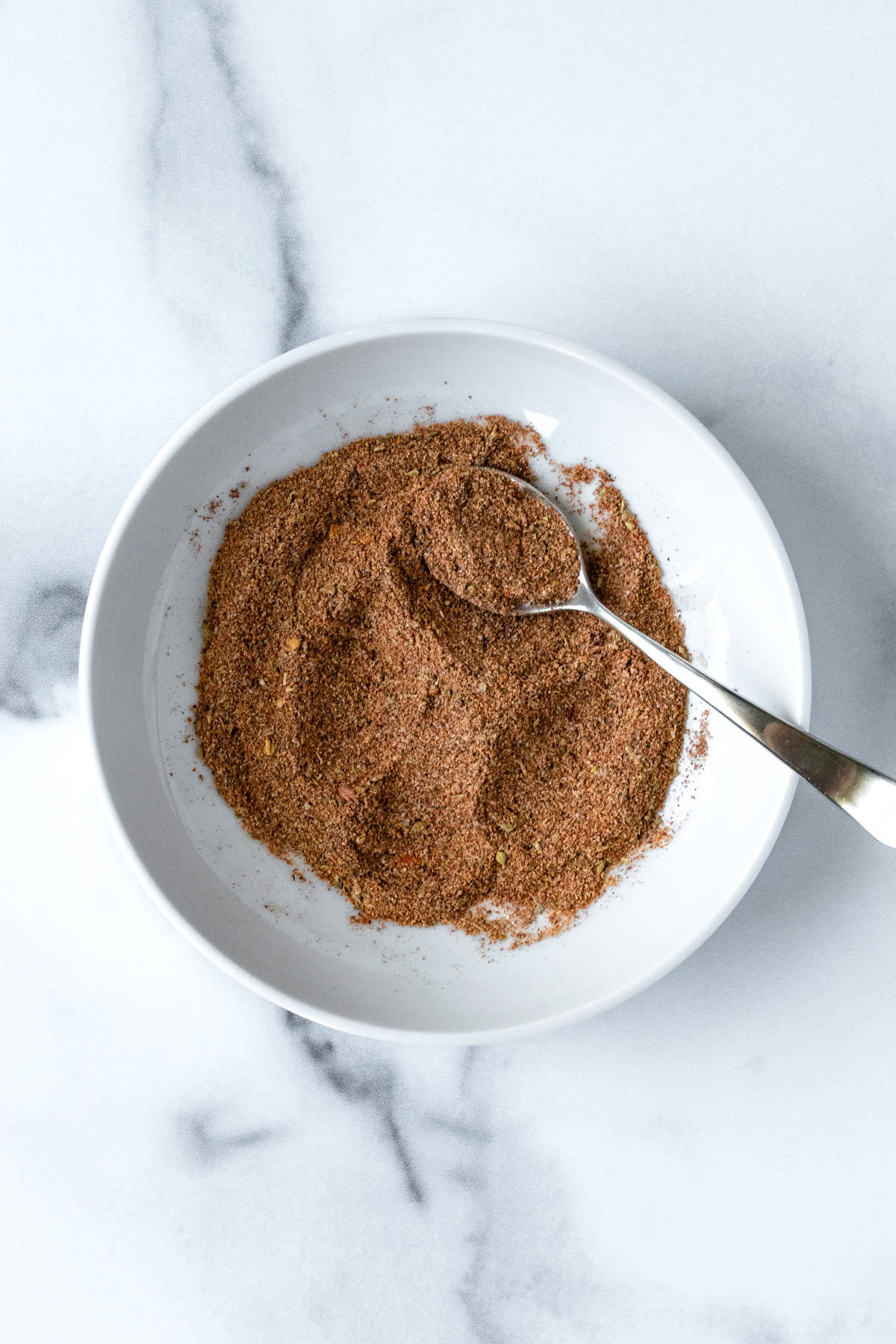 Homemade Ground Turkey Taco Seasoning in a white bowl with a spoon.